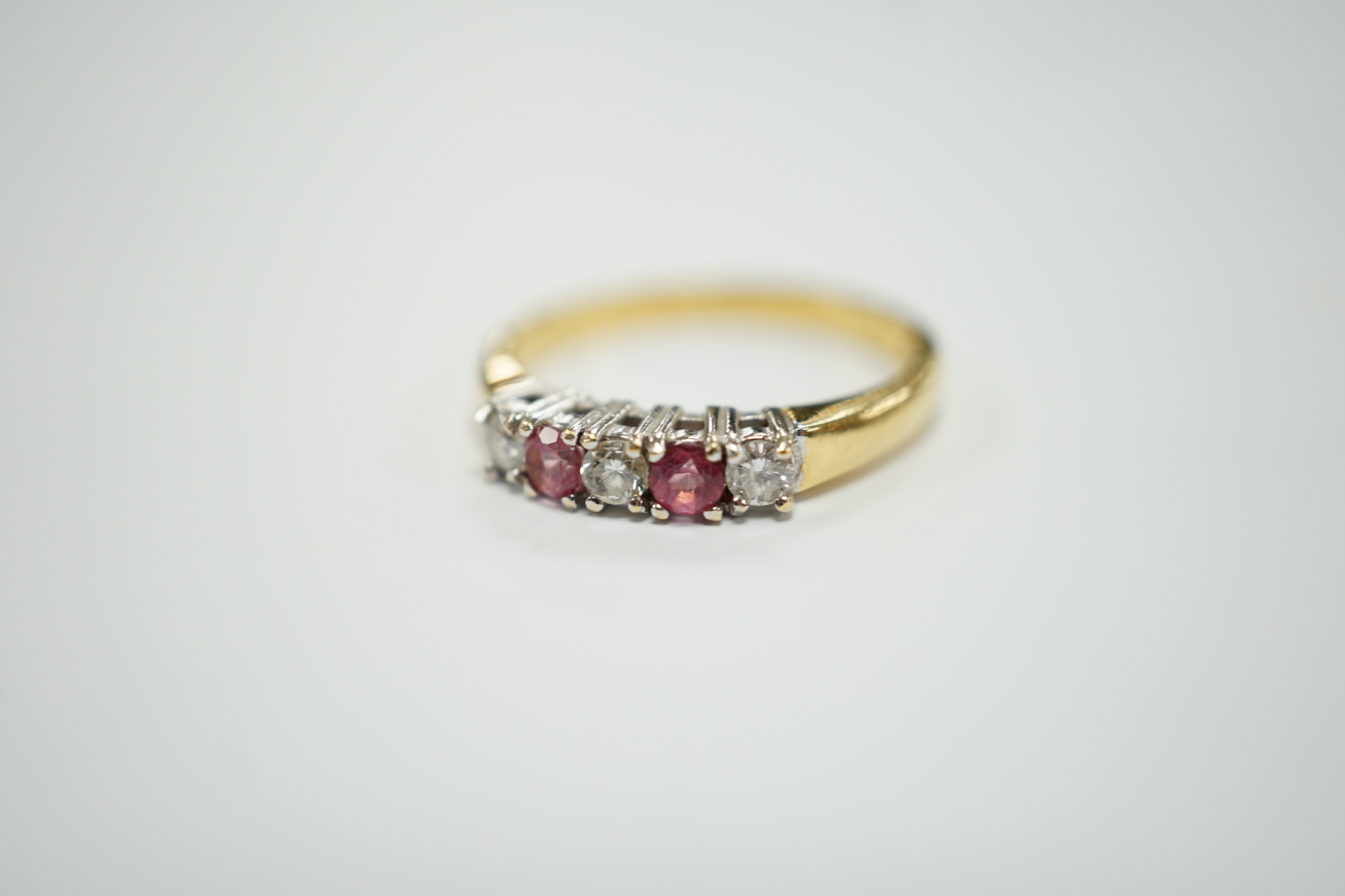An 18ct gold, two stone pink sapphire? and three stone diamond set half hoop ring, size O, gross weight 3.3 grams.